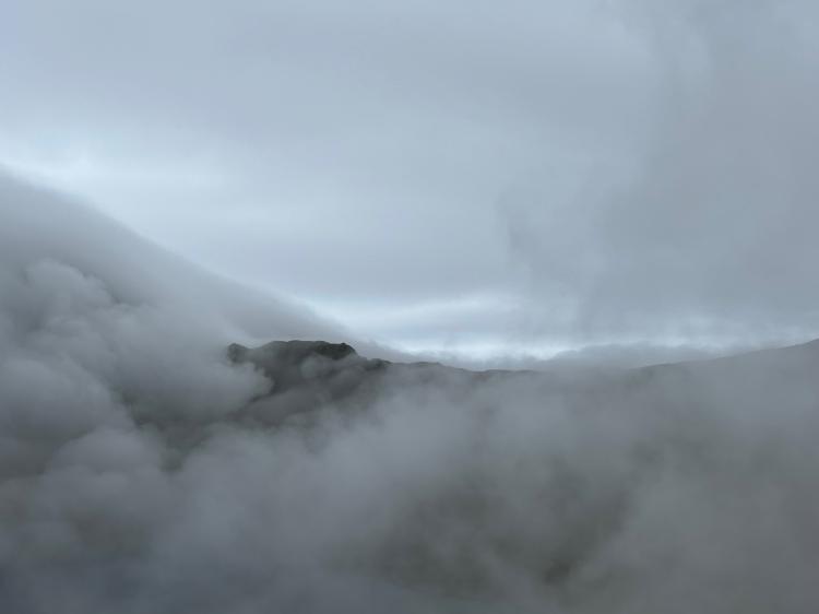 A photo of a mountain ridgeline almost entirely shrouded in cloud